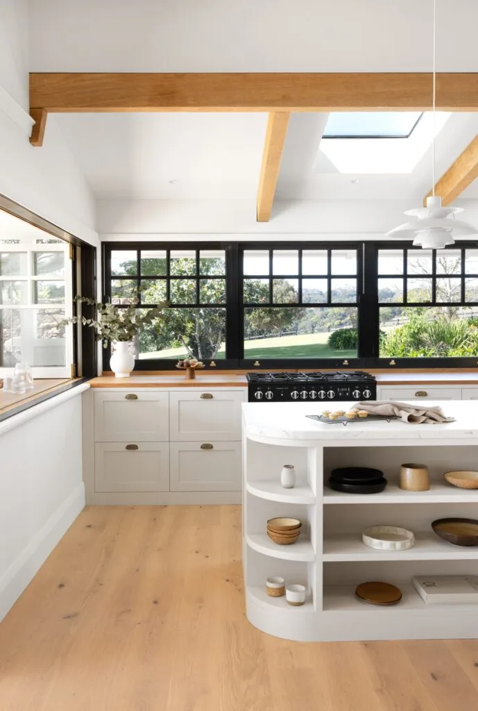 A modern country style kitchen with rosewood timber accents and black-trimmed windows.