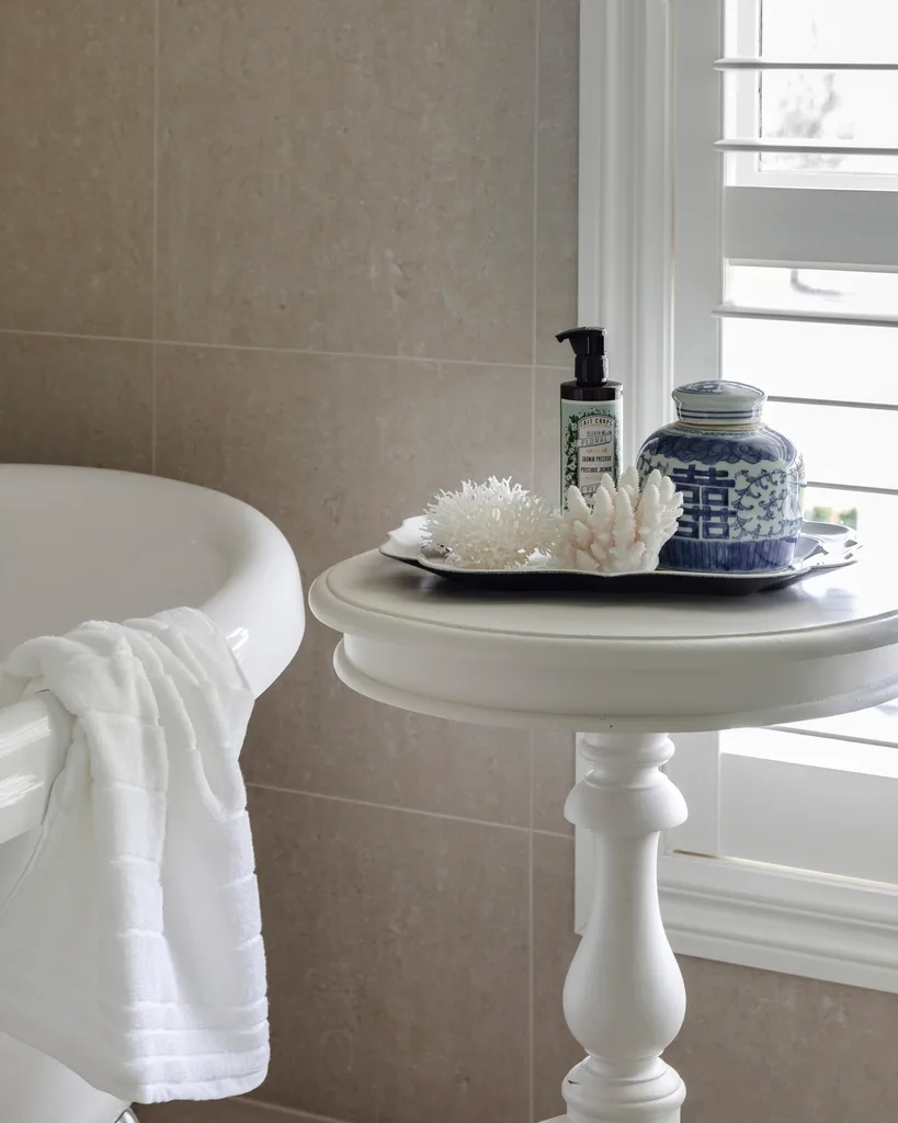 Decorative coral on a white side table by the bath tub.
