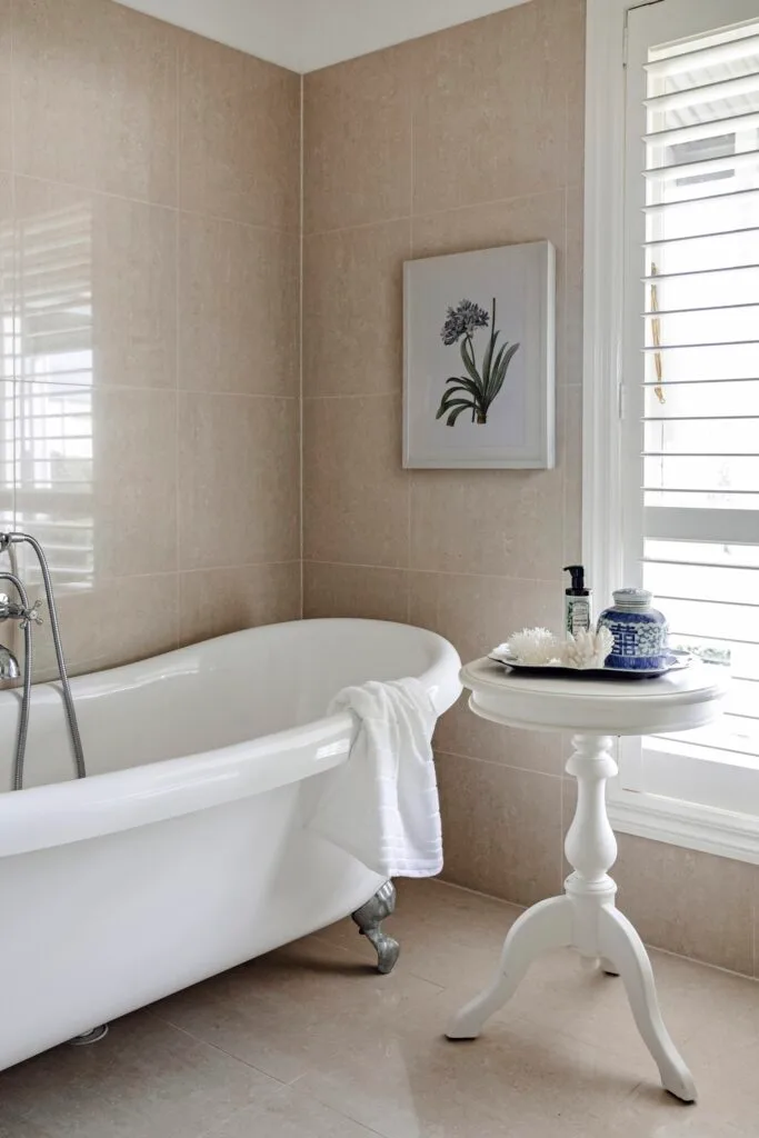 A country style bathroom with a clawfoot tub and pink glazed tiles.