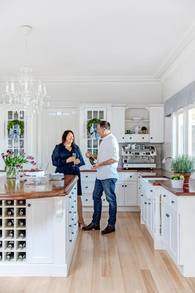 Samantha and David in their country style kitchen with timber accents and white furniture.