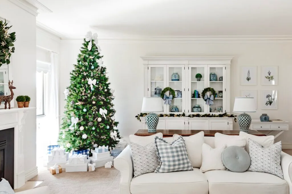 An all-white Hamptons style living room with a Christmas tree by the window.