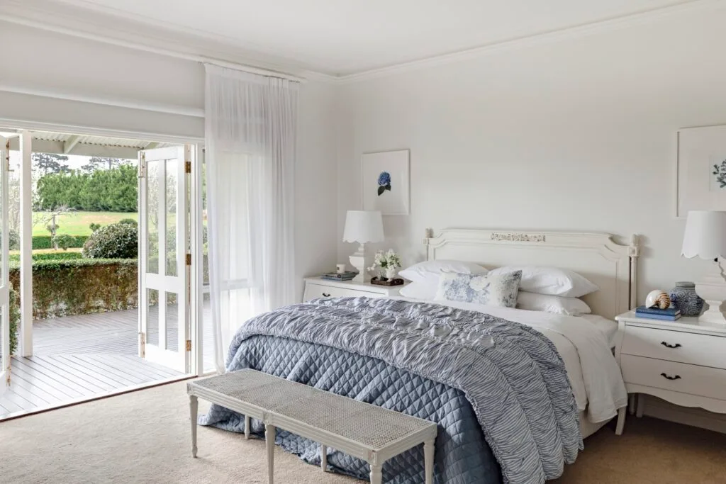 The main bedroom with French doors and classic white and blue furniture.