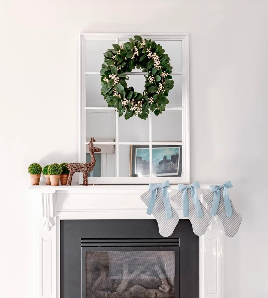 A classic white mantlepiece with a green Christmas wreath and mirror.