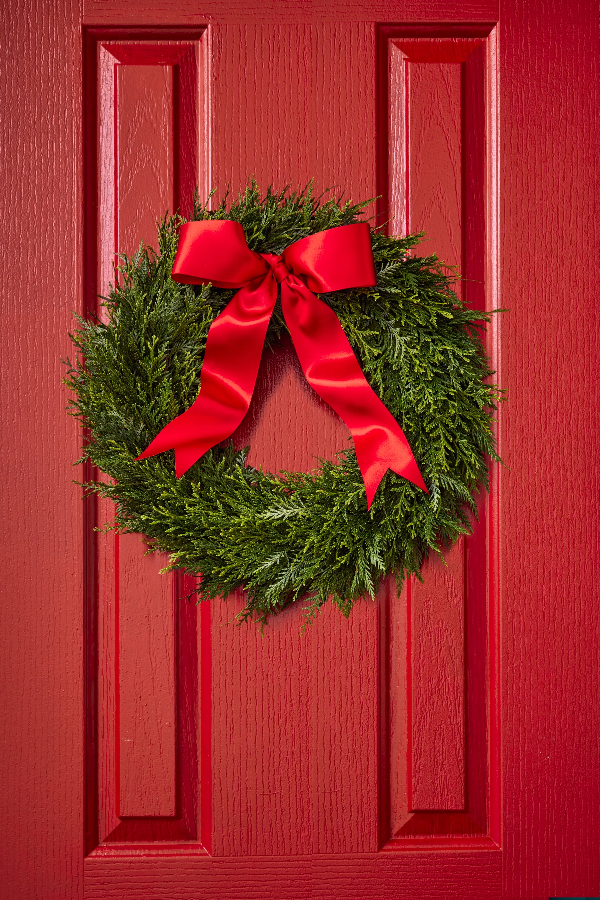 A traditional Christmas wreath of conifer foliage and a red bow.
