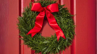 A traditional Christmas wreath of conifer foliage and a red bow.