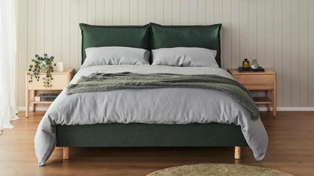 A green fabric bed with grey linens from Ecosa.