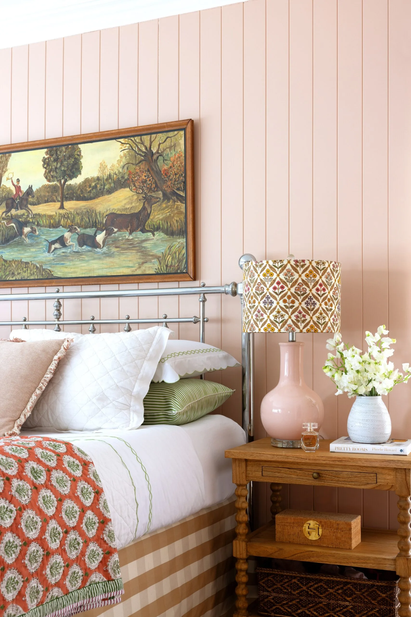 Pastel pink wall panels and a vintage style artwork on a bedroom wall.