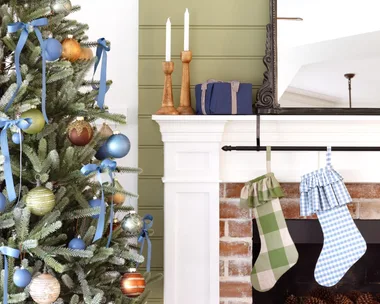 Christmas stockings on a fireplace by a decorated tree.