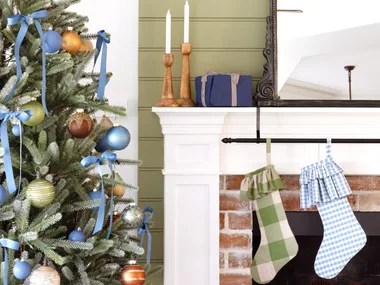 Christmas stockings on a fireplace by a decorated tree.