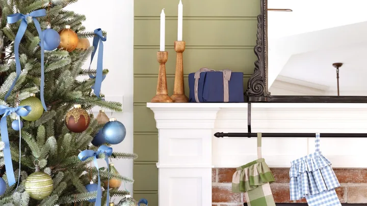 Christmas stockings on a fireplace by a decorated tree.