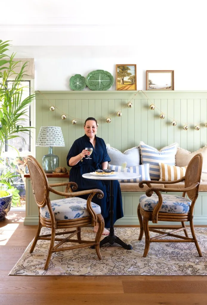 Hayley sitting in the games room on a light green panelled bench alongside upholstered furniture.