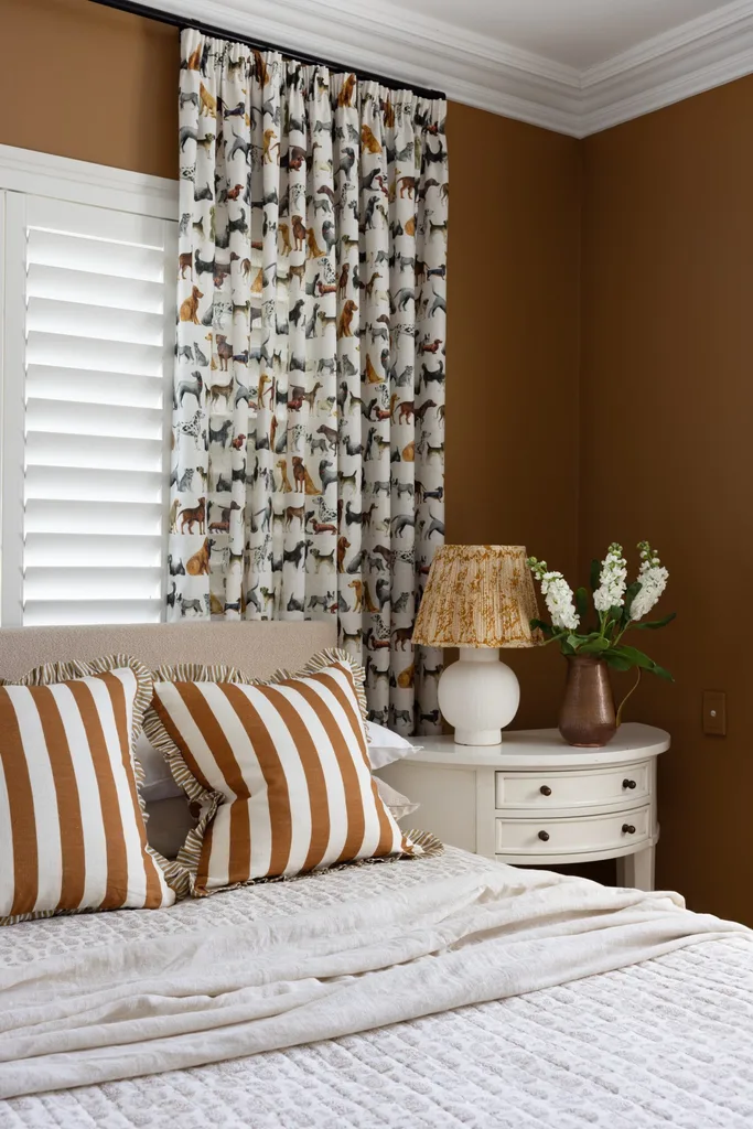 A children's bedroom with chocolate brown walls and patterned curtains.