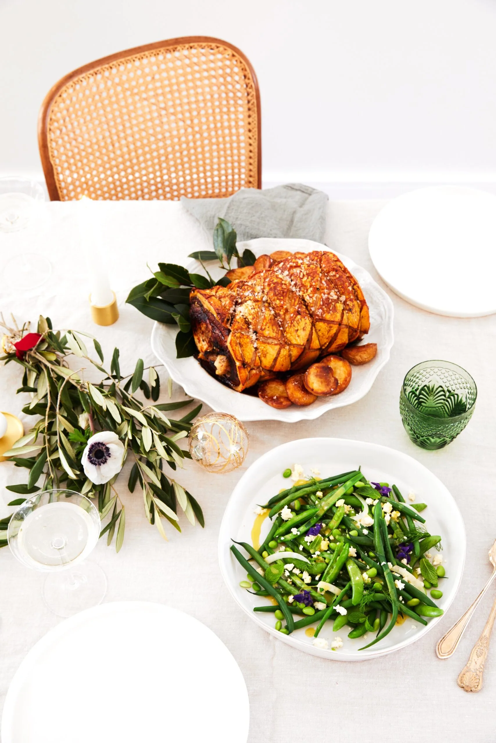 Rolled pork loin with apple and thyme and a bean salad on a white Christmas tablescape.