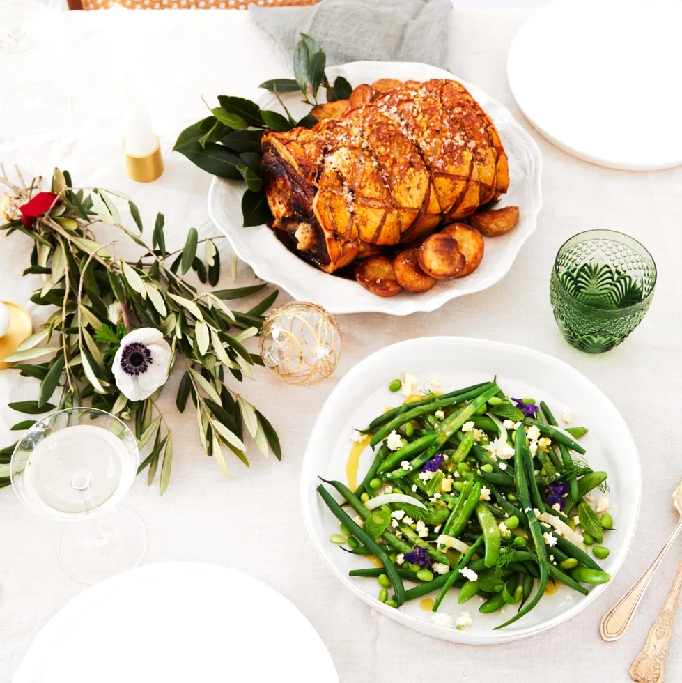 Rolled pork loin with apple and thyme and a bean salad on a white Christmas tablescape.