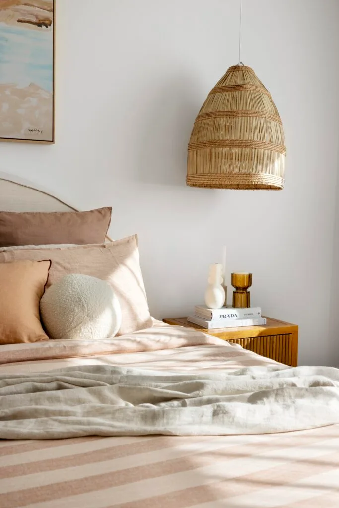 The main bedroom in a neutral palette with a wicker hanging lampshade.