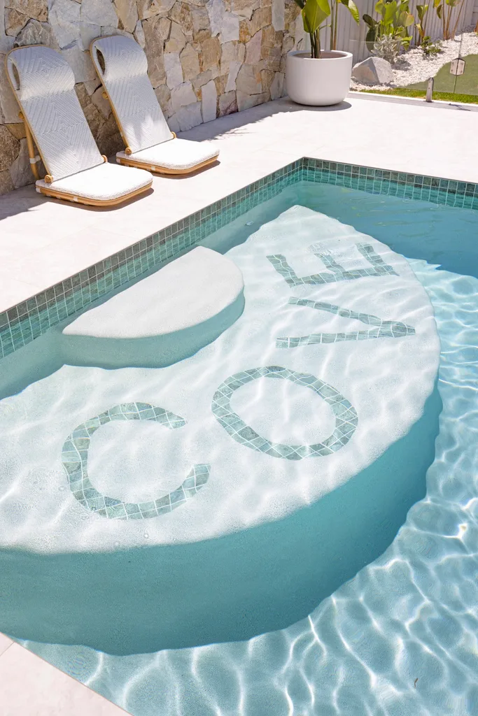 A resort-style pool and white pool loungers.