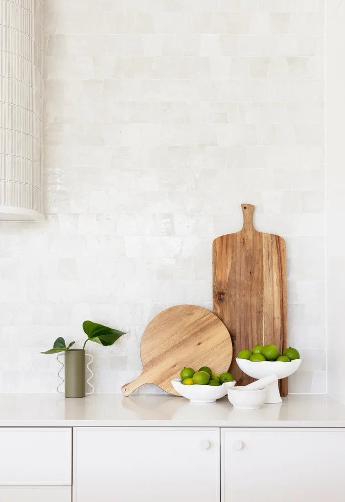 White gloss kitchen tiles and timber cutting boards on a benchtop.