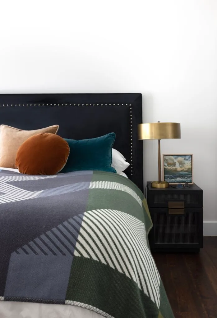 The guest bedroom with a black velvet bedhead and dark bed cushions.