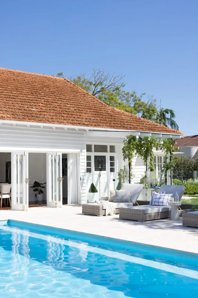 The outdoor pool and entertaining area with loungers and an arbour with climbing plants.