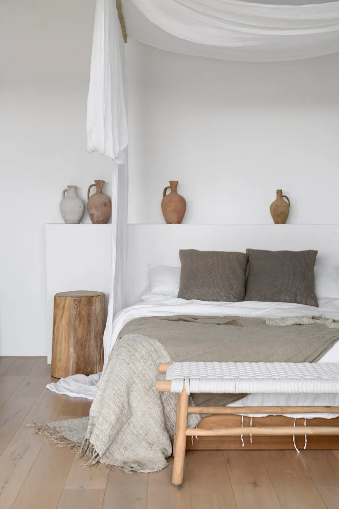 The main bedroom with white and timber décor and a bed canopy.