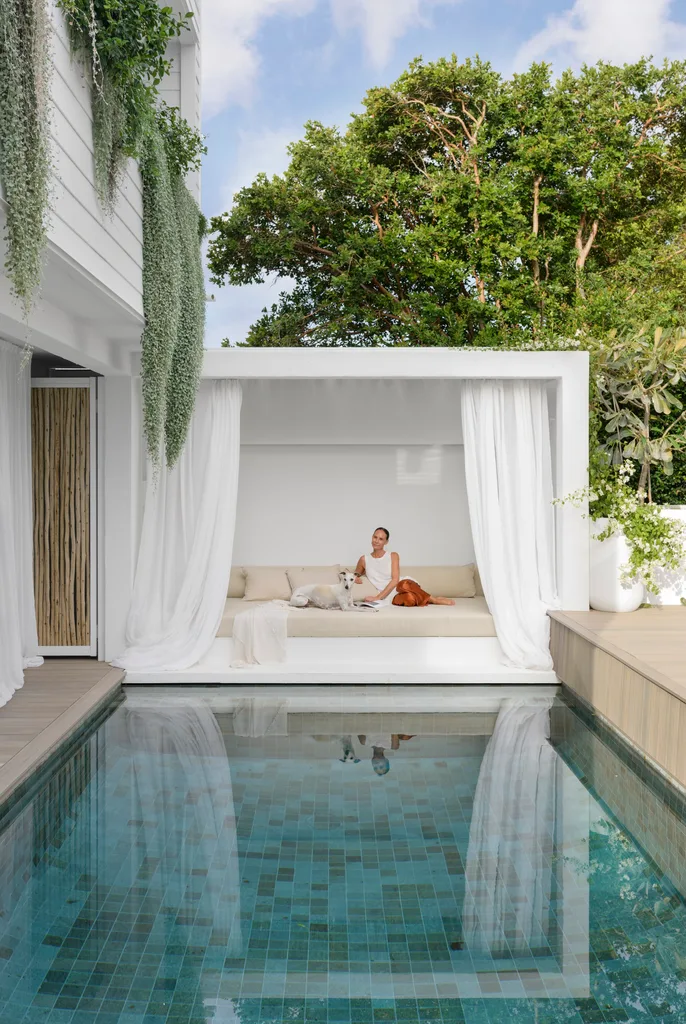 Artist Cinnamon in the white curtained pool cabana and brilliant pool landscaping ideas.