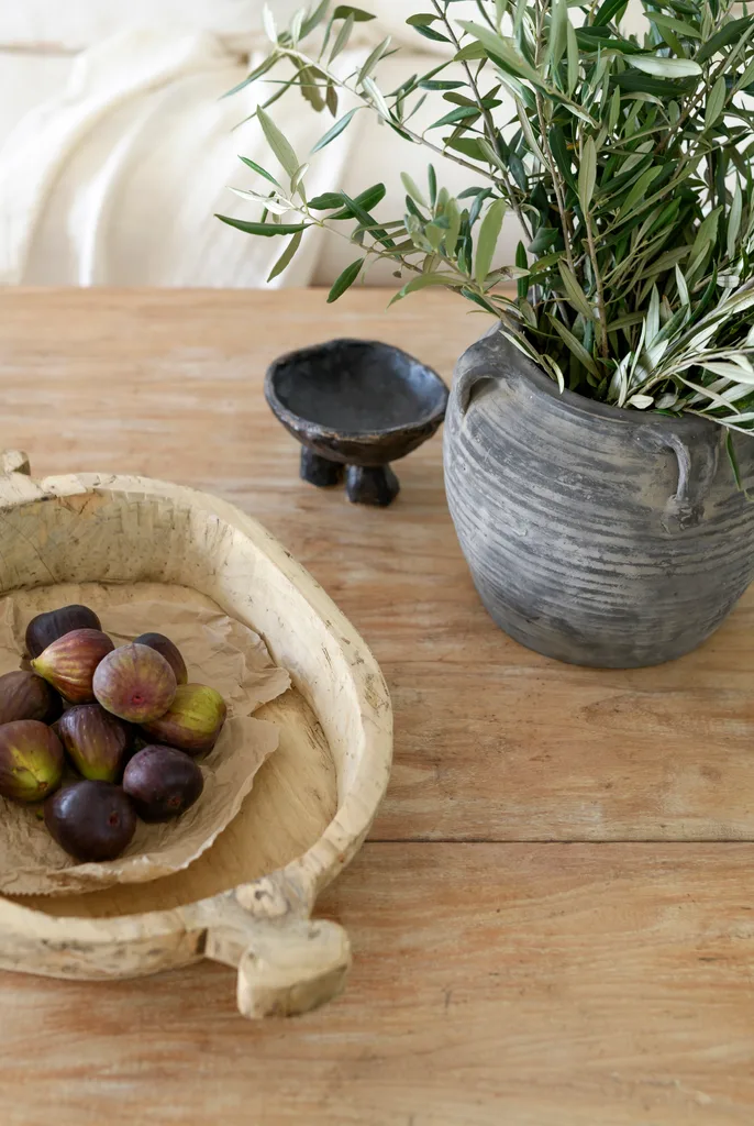 A black rustic vase and timber tray on the coffee table.