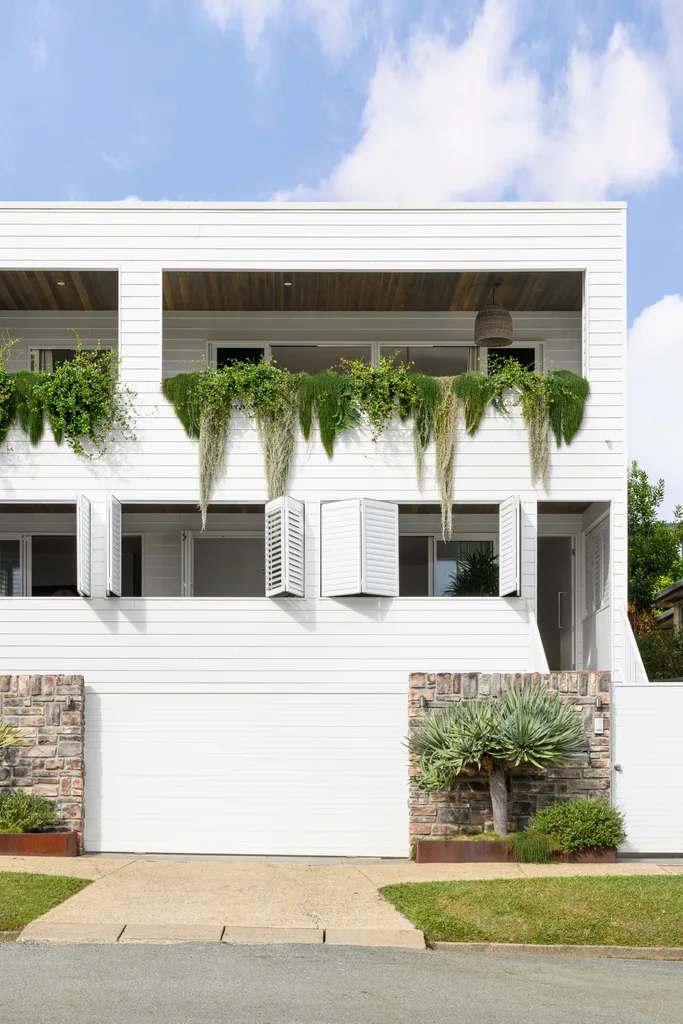 A white cladded front facade with draping greenery.