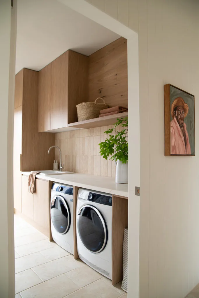 Modern farmhouse laundry with timber joinery and beige floor and backsplash tiles.