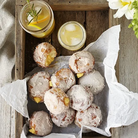A wooden tray with orange and custard-filled doughnuts.