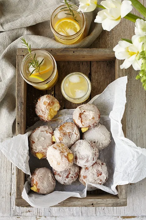 A wooden tray with orange and custard-filled doughnuts.