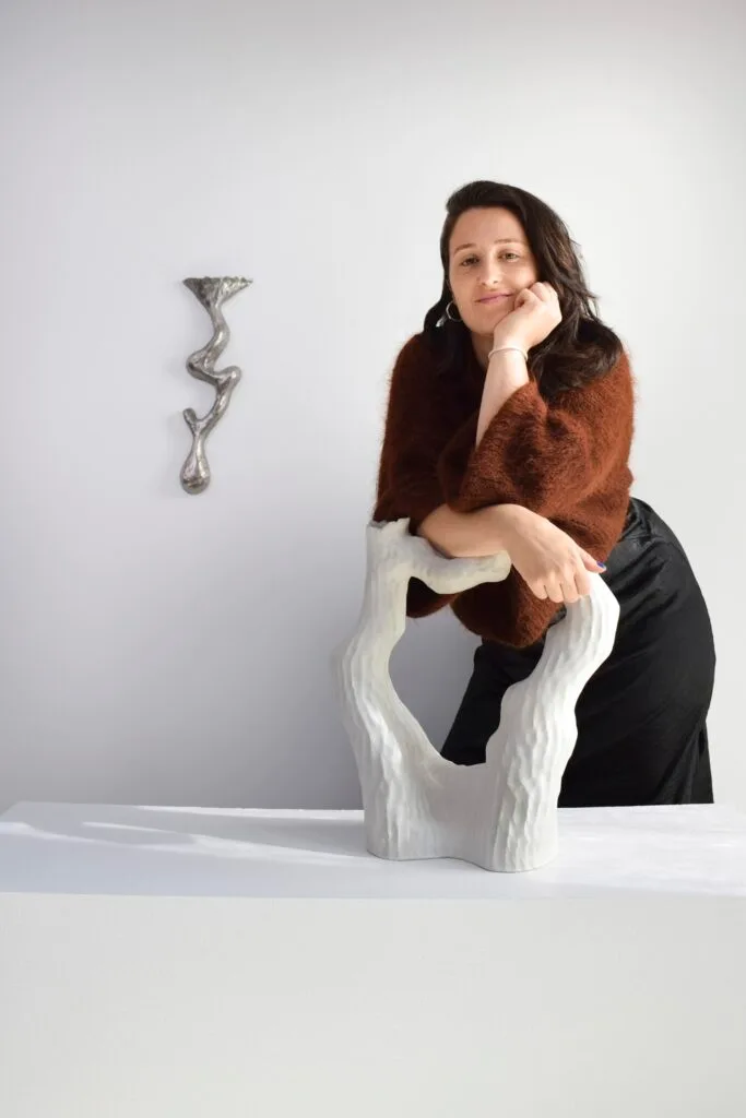 A portrait of artist Kerryn Levy with a white sculpted artwork.