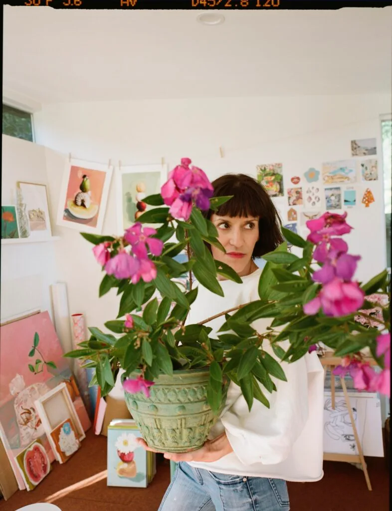 A portrait of artist Nicole Nelius holding flowers.