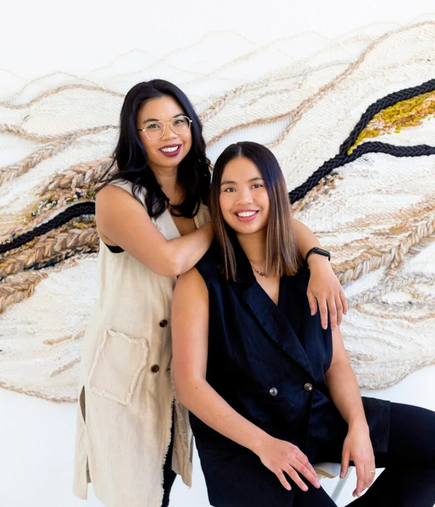 Australian artists Kass and Lauren Hernandez by one of their woven artworks.