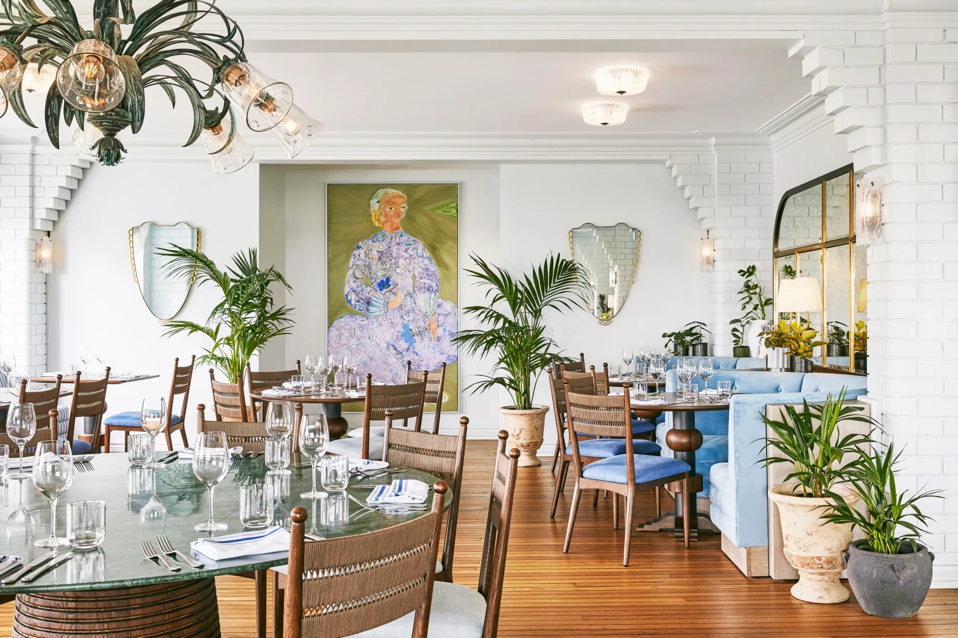 A white heritage style dining room with blue and timber furniture and tropical plants.