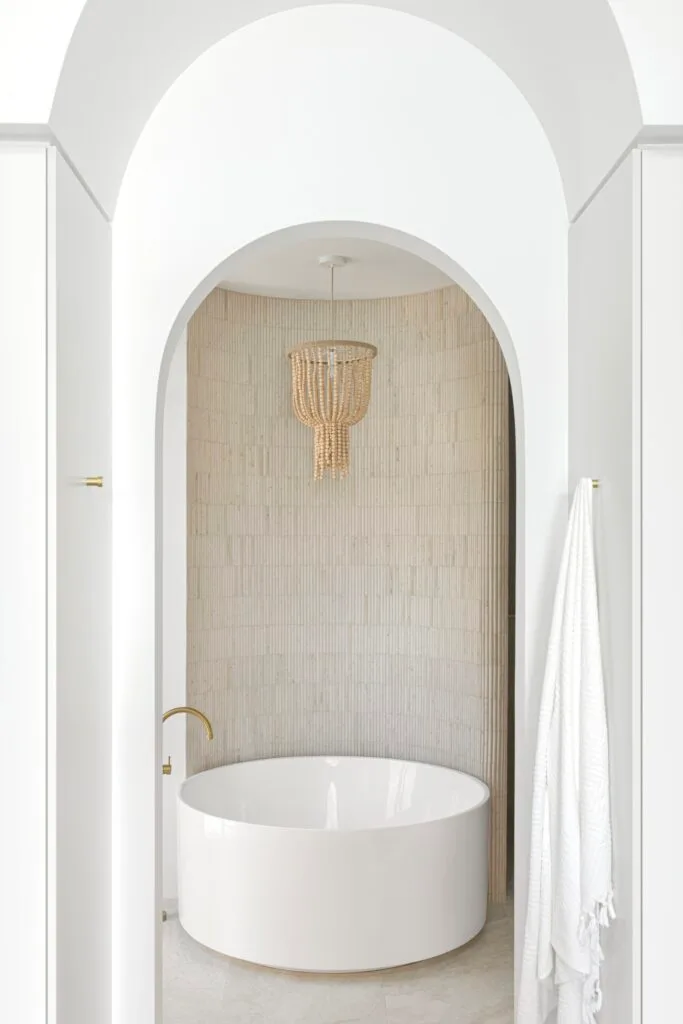 A luxury ensuite with a freestanding circular bath and beaded pendant.