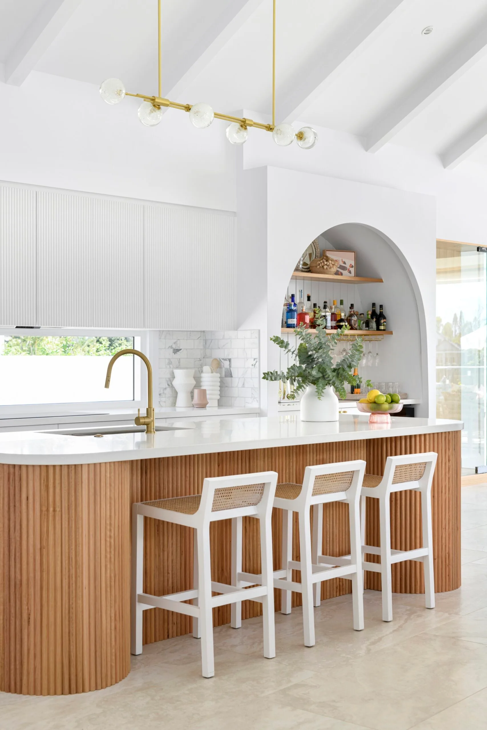 A white and timber coastal style kitchen with a fluted timber island.