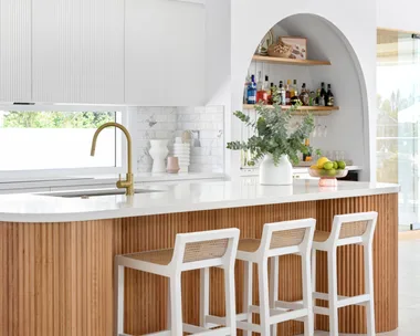 A white and timber coastal style kitchen with a fluted timber island.