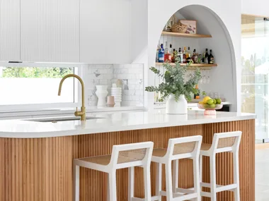 A white and timber coastal style kitchen with a fluted timber island.