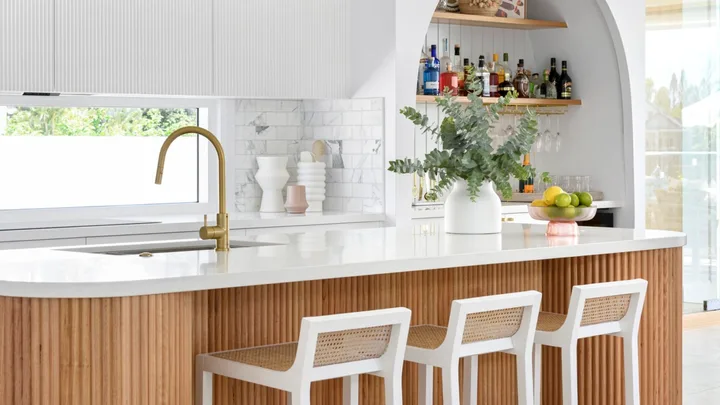 A white and timber coastal style kitchen with a fluted timber island.