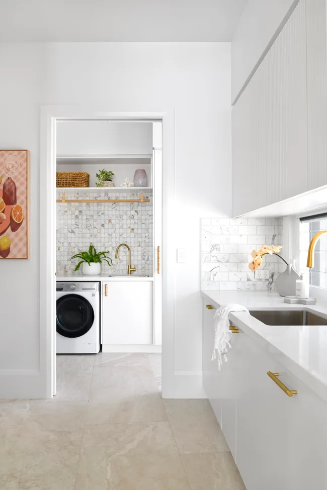 A coastal white kitchen looking into the laundry room.