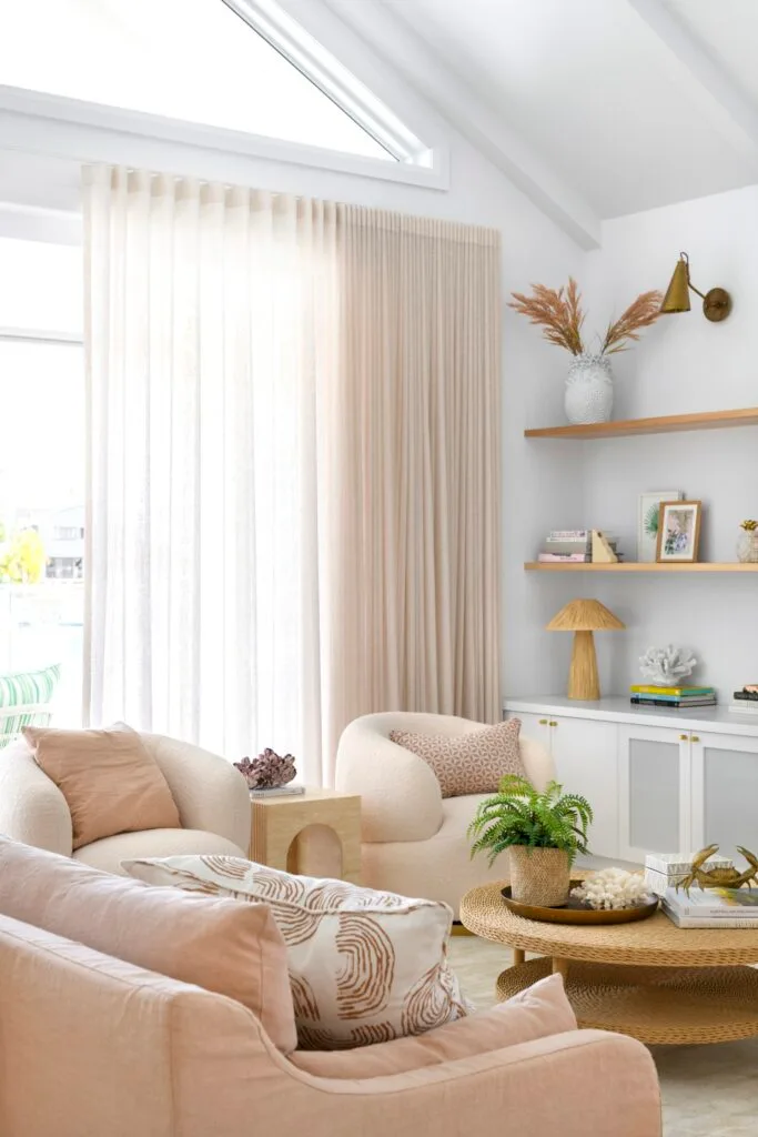 A pink pastel living area with soft round chairs and a rattan coffee table.