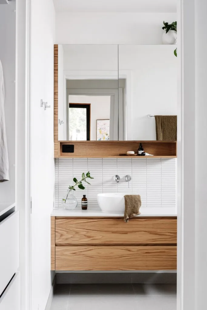 A white and timber ensuite with white finger tiles.