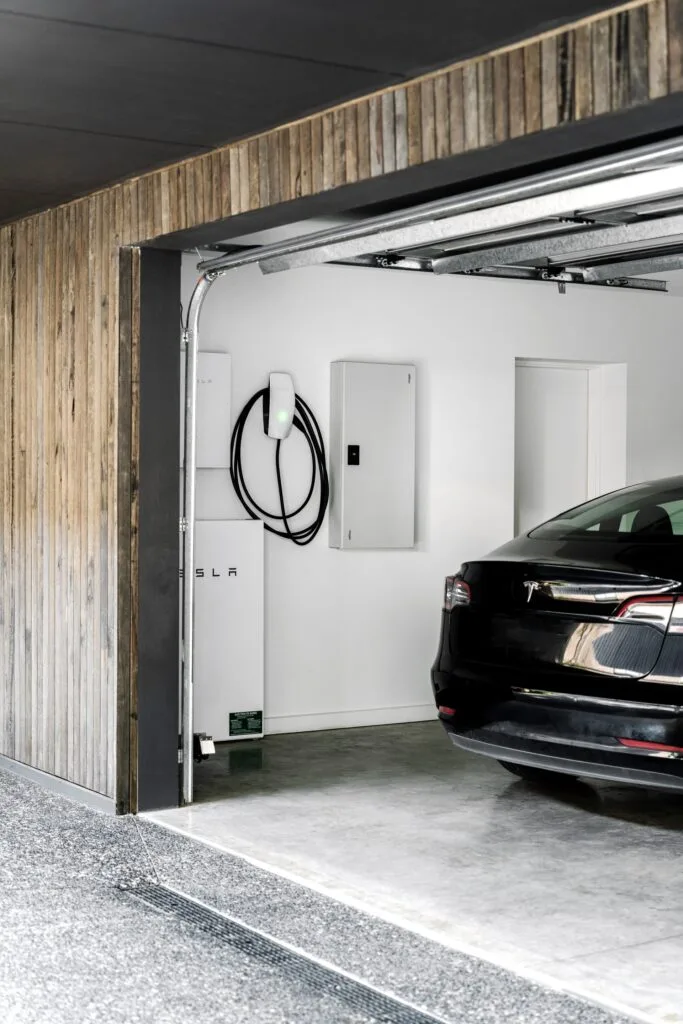 Timber cladded garage with a Tesla and an electric charging station.