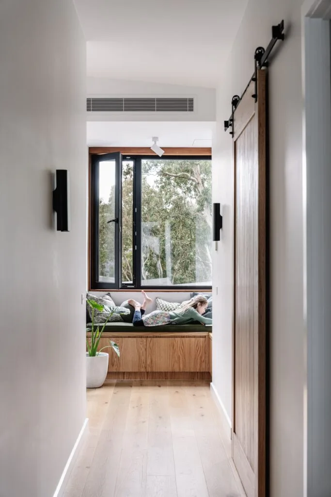 The hallway leading a reading nook below an open window.