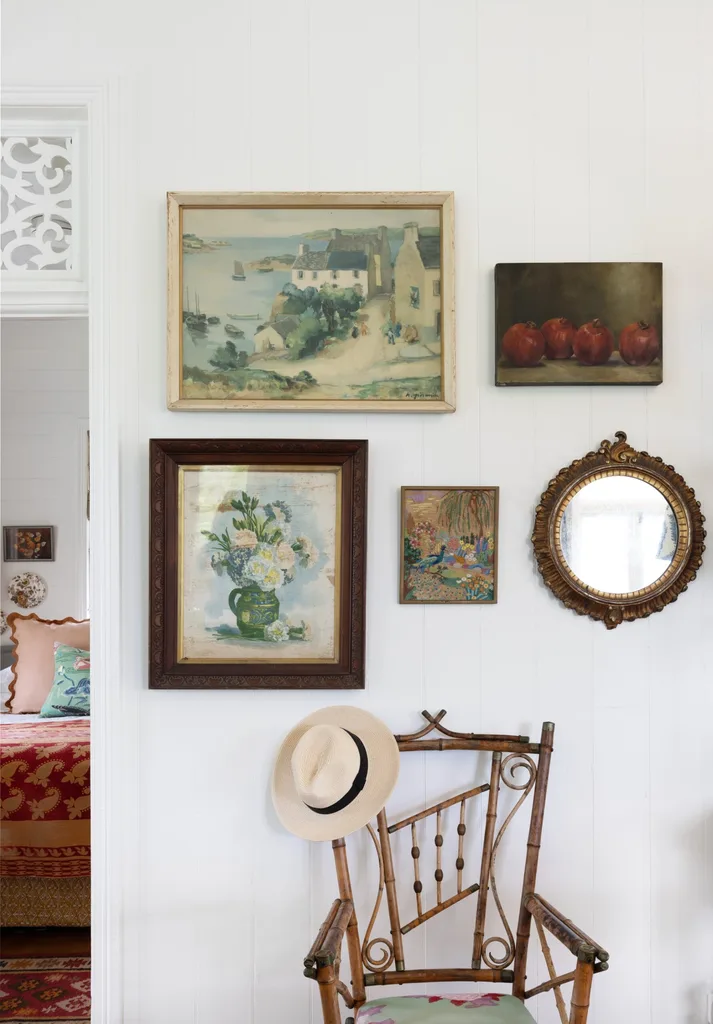 An antique bamboo chair in the living area below a gallery wall.