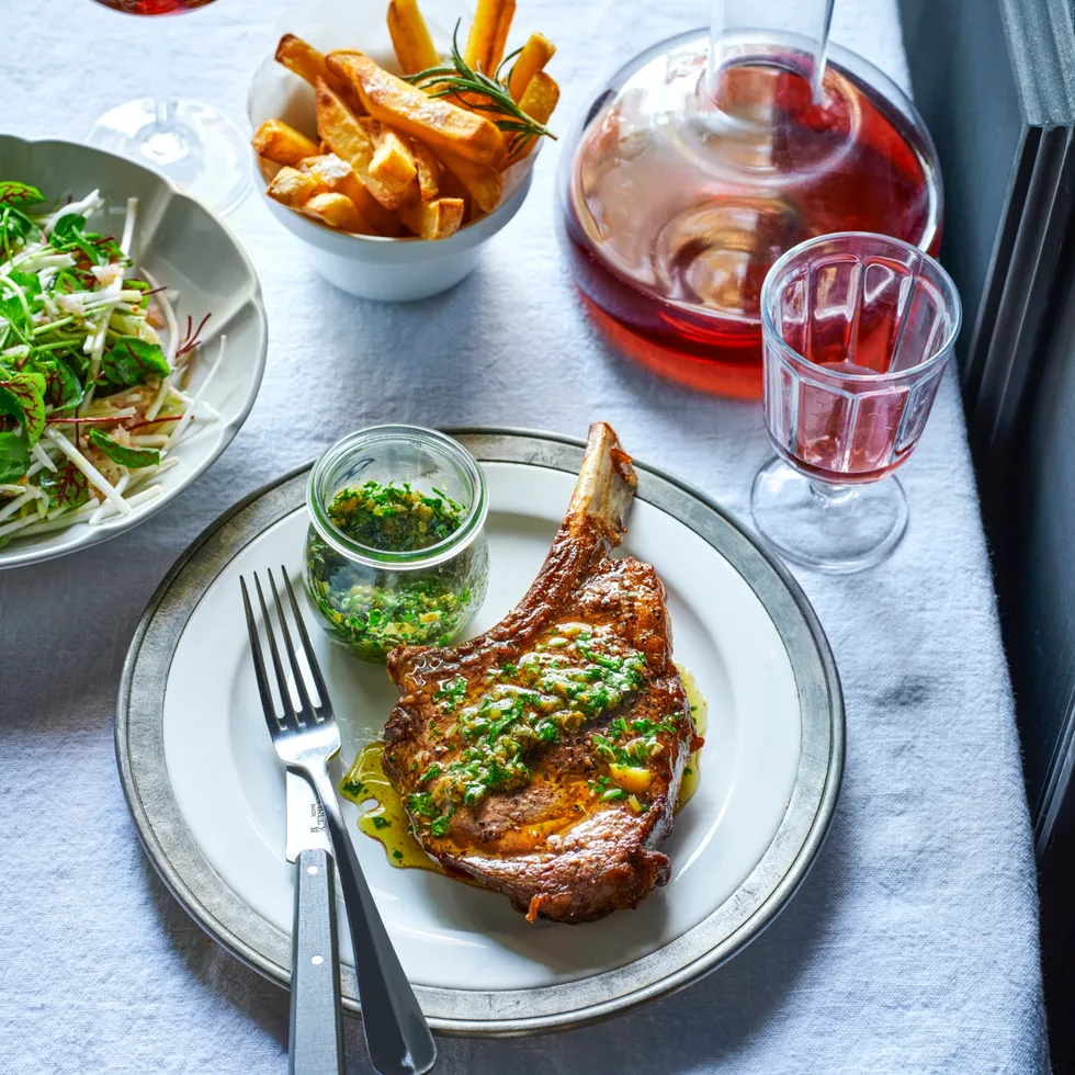 A cut of steak on a plate with a side of fries and ravigot sauce.