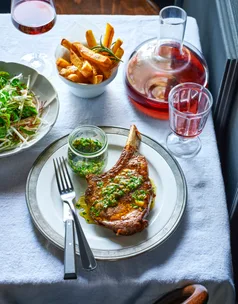 A cut of steak on a plate with a side of fries and ravigot sauce.