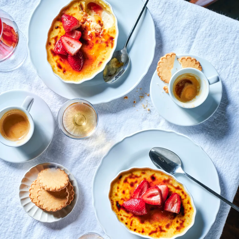 Two bowls of crème brulee topped with strawberries.