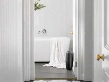 An all-white hallway with a checked floor leading to a bathroom.