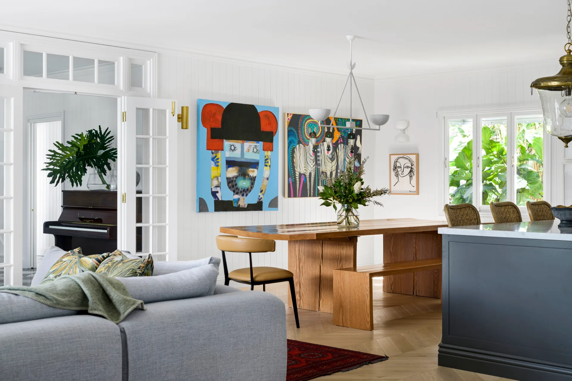 A dining room with a timber table, bright wall art and French open doors.